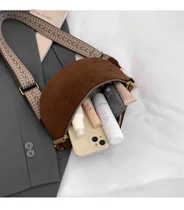 Detail of a brown suede crescent bag with ethnic wide strap and storage for cosmetics