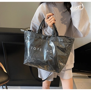 Detail of black glossy tote bag with white text print and adjustable shoulder strap