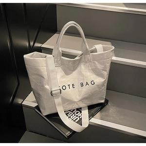 Detail view of large white tote bag with crinkled texture and black letter print