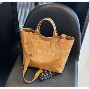 Detail of large brown tote bag with wrinkled texture, lettering and adjustable strap