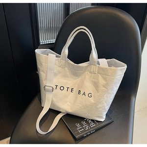 Detail of white tote bag with DuPont paper texture and black text on a minimalist chair