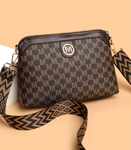 Detail of vintage brown crossbody bag with M-pattern and stylish wide shoulder strap