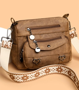 Detail of brown faux leather crossbody bag with ethnic patterned strap and heart charms