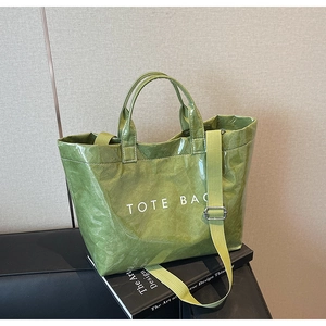 Detail of green tote bag featuring crinkled texture and white TOTE BAG typography