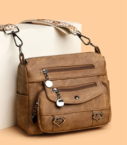 Detail of dark brown vintage faux leather crossbody bag with multiple zip pockets