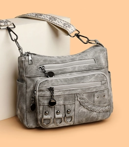 Detail of vintage gray crossbody bag featuring washed PU leather and retro metal rings