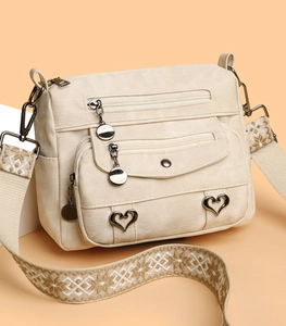 Detailed close-up of a vintage beige canvas crossbody bag with multiple zip pockets