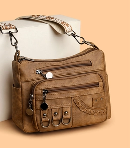 Close-up of vintage faux leather crossbody bag with multiple pockets and bronze hardware