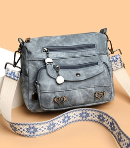 Detail of blue denim textured crossbody bag with heart metal decor and jacquard strap