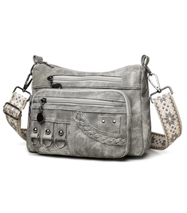 Detail view of multi-pocket grey crossbody bag with vintage washed texture and woven strap
