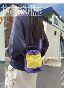 Outdoor shot of the colorful mini drawstring bucket bag worn on a model back