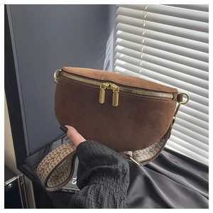 Detail of brown suede waist bag showing metal zippers and patterned woven shoulder strap
