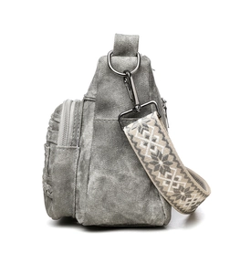 Detail of grey canvas crossbody bag with gunmetal zippers and ethnic woven strap