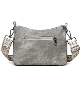 Detail view of washed canvas crossbody bag with ethnic embroidered strap and metal hooks