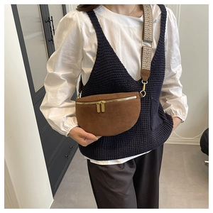 Detail of brown suede crescent bag featuring golden hardware and woven jacquard strap