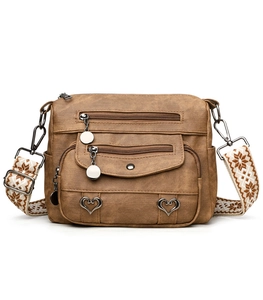 Detail view of brown leather crossbody bag with multiple zippers and heart charms