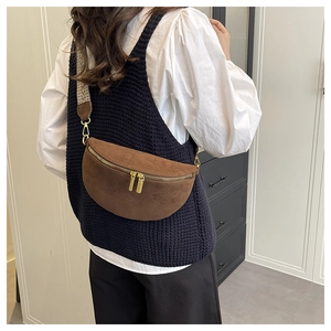 Detail of brown faux suede crescent chest bag with patterned woven strap and gold hardware