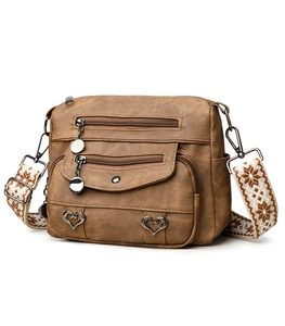 Detailed view of brown faux leather crossbody bag with vintage texture and heart charms