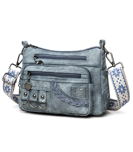 Close-up of vintage blue denim crossbody bag with multiple pockets and patterned strap