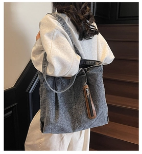Détail du sac fourre-tout en denim délavé avec poche zippée et bordures en cuir brun