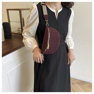 Detail of burgundy crossbody chest bag with geometric woven strap and gold metal hardware
