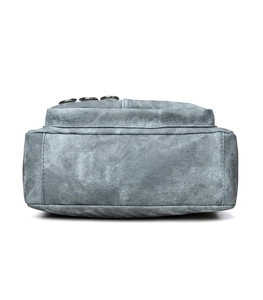 Detail of light blue denim crossbody bag showing washed texture and metal hardware zippers