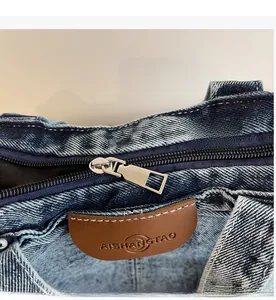 Détail de la fermeture éclair et de l'écusson en cuir sur un sac cabas en denim