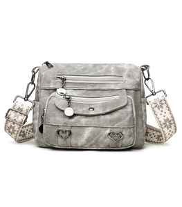 Close-up of vintage grey multi-pocket crossbody bag with heart charm and woven strap