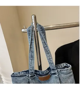Détail d'un sac cabas en denim délavé avec poignées robustes et écusson en cuir brun