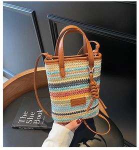 Detail of colorful striped woven mini bag with brown leather handles and shoulder strap