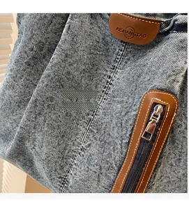 Détail du tissu en denim délavé avec empiècement en cuir brun et fermeture éclair métallique