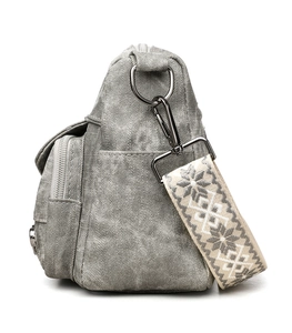 Detail of grey vintage canvas crossbody bag with ethnic embroidered strap and metal hardware