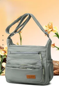 Close-up of light grey multi-pocket nylon crossbody bag with SOSIDI BAG leather patch