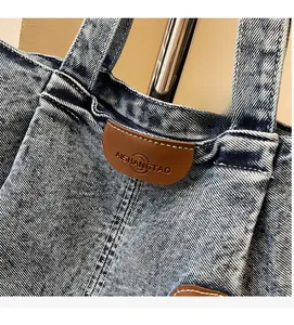 Gros plan sur un cabas en denim délavé avec empiècement en cuir brun et surpiqûres