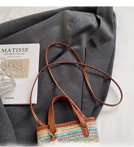 Detail of multi-color woven straw crossbody bag placed on a grey blazer and art book