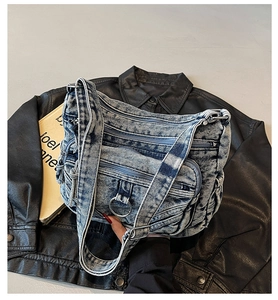 Détail du sac bandoulière en jean bleu clair avec plusieurs poches zippées et anneaux métal