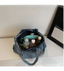 Vue intérieure montrant la grande capacité du cabas en jean délavé avec accessoires