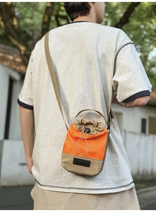 Outdoor shot of an orange and khaki drawstring crossbody water bottle bag for summer