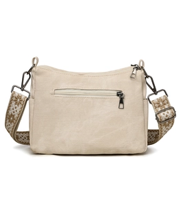 Detail of canvas crossbody bag with ethnic jacquard strap and zip pocket on white background