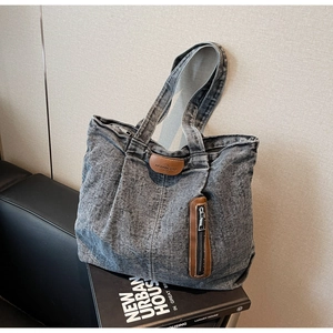 Détail du sac cabas en denim délavé gris avec poche en cuir marron et fermeture éclair