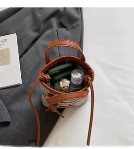 Interior view of colorful straw bucket bag with brown leather strap showing storage space