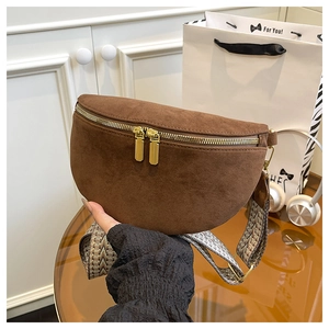 Close-up of brown suede crossbody bag with gold zippers and geometric woven strap