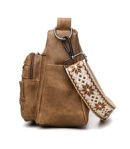 Detail of soft brown crossbody bag with multi-zipper pockets and geometric woven strap