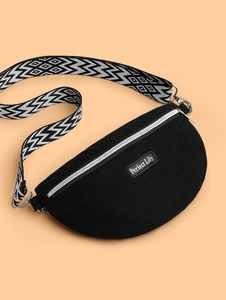Détail de la texture velours noir et de la sangle à motifs sur le sac demi-lune