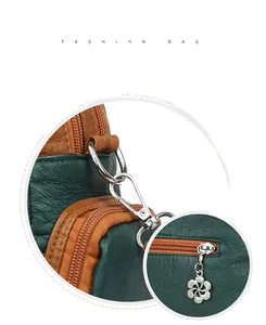 Detail of silver floral zipper pull and metal hook on green textured leather shoulder bag