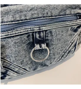 Gros plan sur le denim délavé avec anneau en métal argenté et détail de fermeture