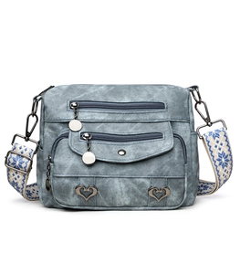 Detail view of denim crossbody bag with multiple zippers and heart-shaped metal buckles