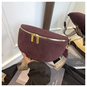 Detail view of burgundy suede waist bag featuring dual gold zippers and jacquard strap