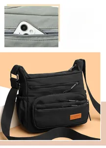 Macro shot of multi-pocket black nylon crossbody bag showing compartments and durable zippers