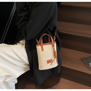Detail of woven straw handbag with brown leather trim and detachable shoulder strap